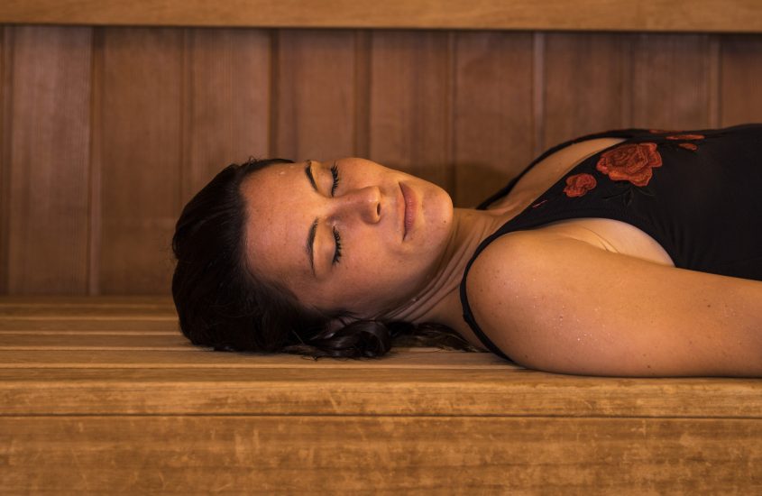 A young woman relaxes in a sauna