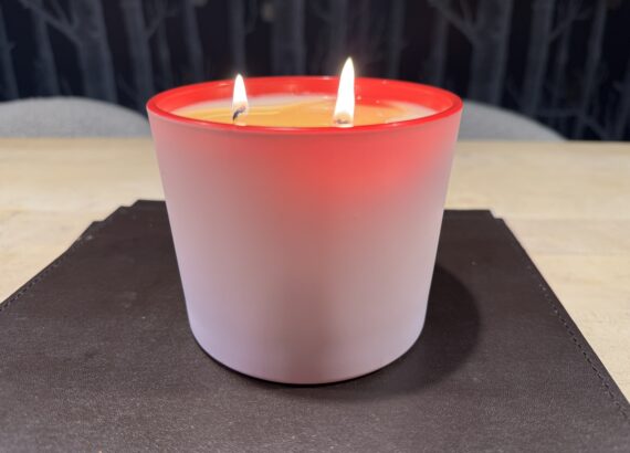 A three-wick scented candle burns on a kitchen table.